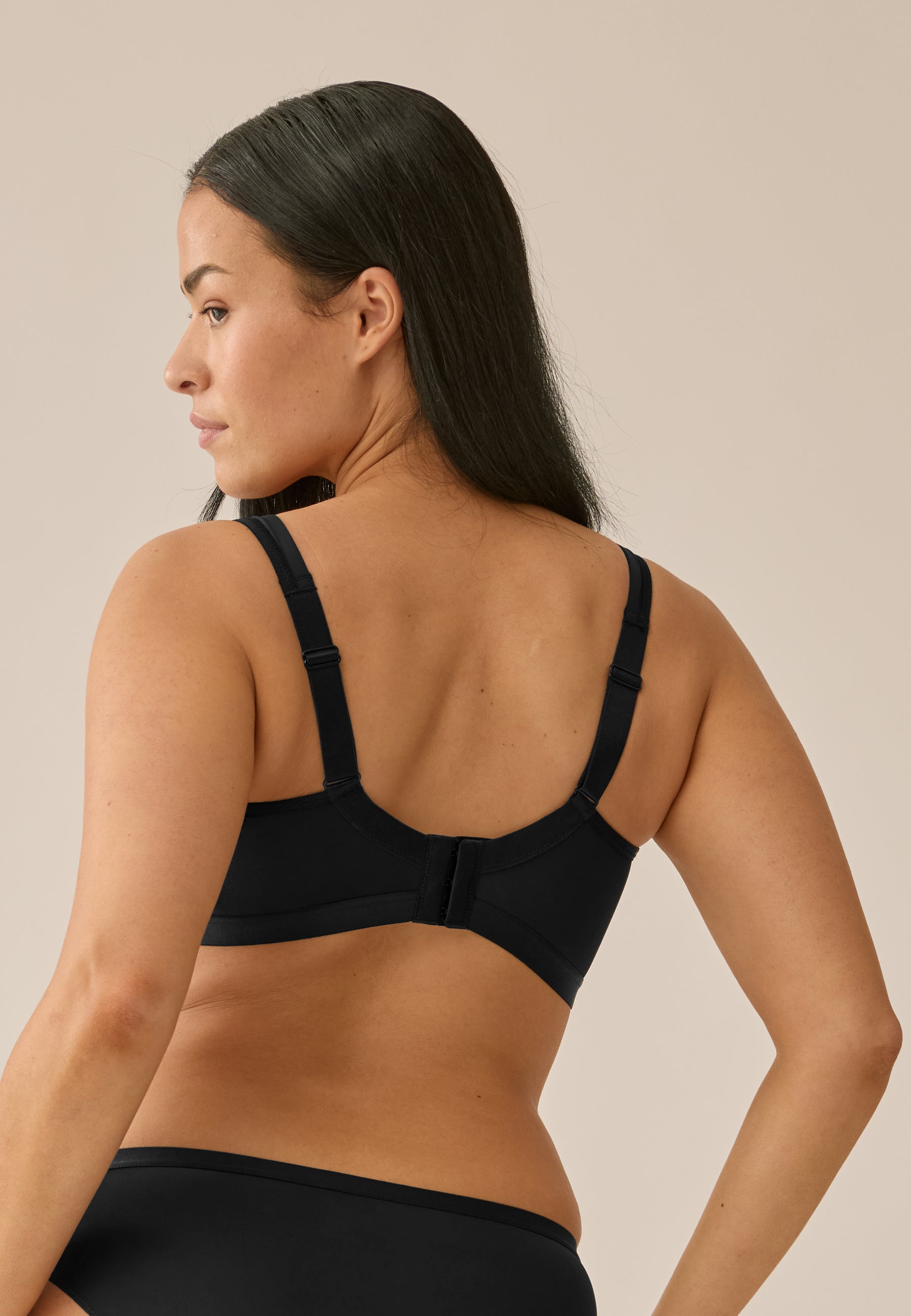 Achterzijde van vrouw die de minimizer bh in de kleur zwart van het merk Naturana draagt