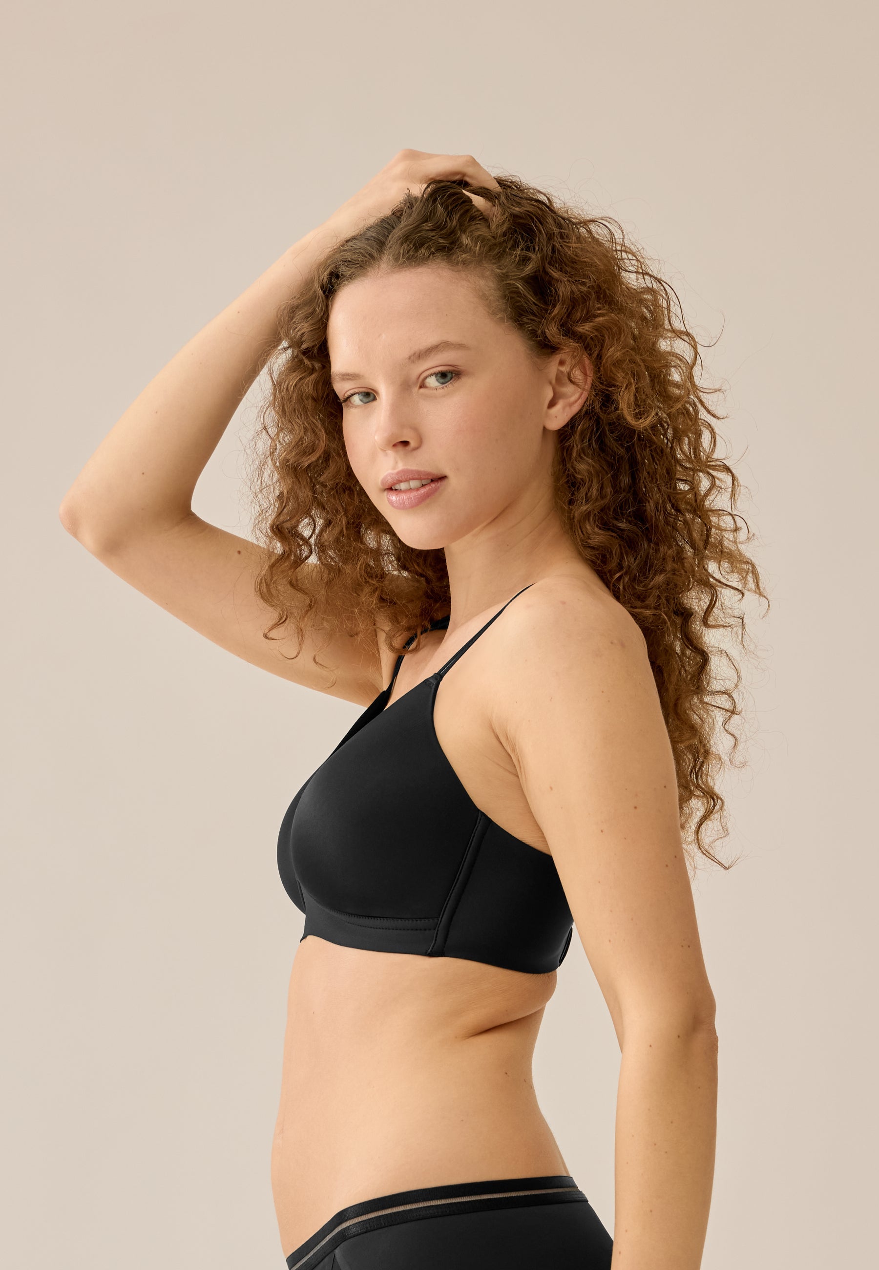 Zijde van vrouw die de soft bh met mesh detail in de kleur zwart van het merk Naturana draagt