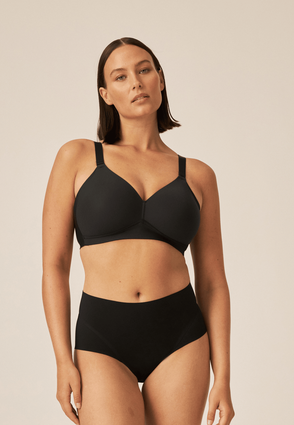 Voorzijde van vrouw die de side smoother bh en high waist slip in de kleur zwart van het merk Naturana draagt