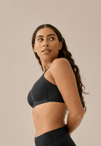 Zijde van vrouw die de side smoother bh in de kleur zwart van het merk Naturana draagt