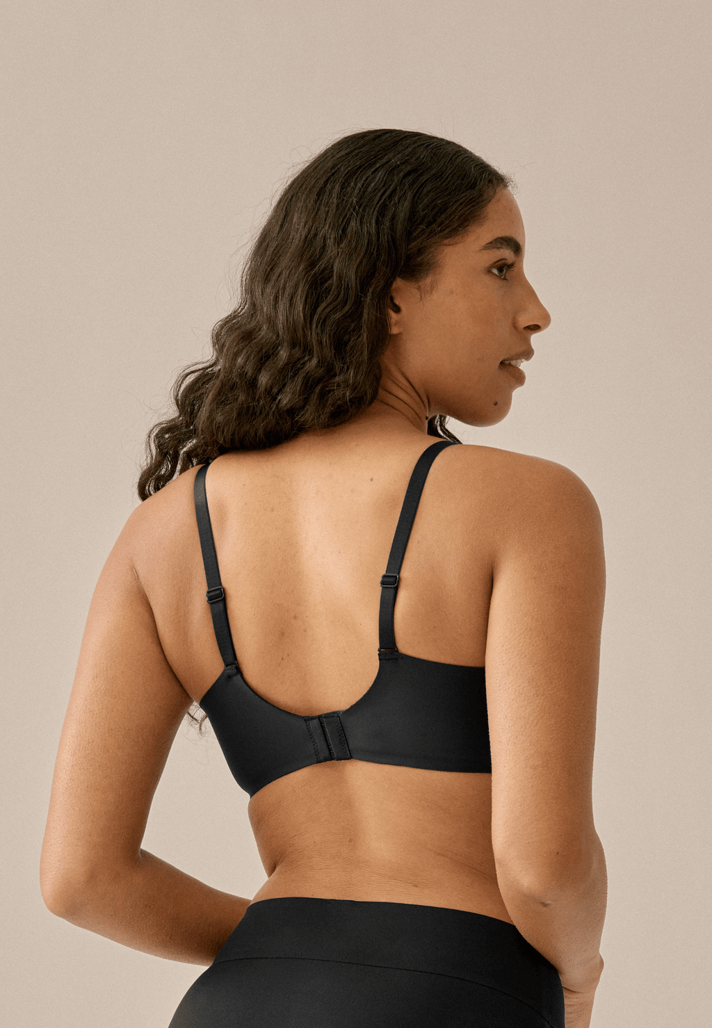 Achterzijde van vrouw die de side smoother bh in de kleur zwart van het merk Naturana draagt