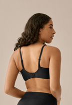 Achterzijde van vrouw die de side smoother bh in de kleur zwart van het merk Naturana draagt