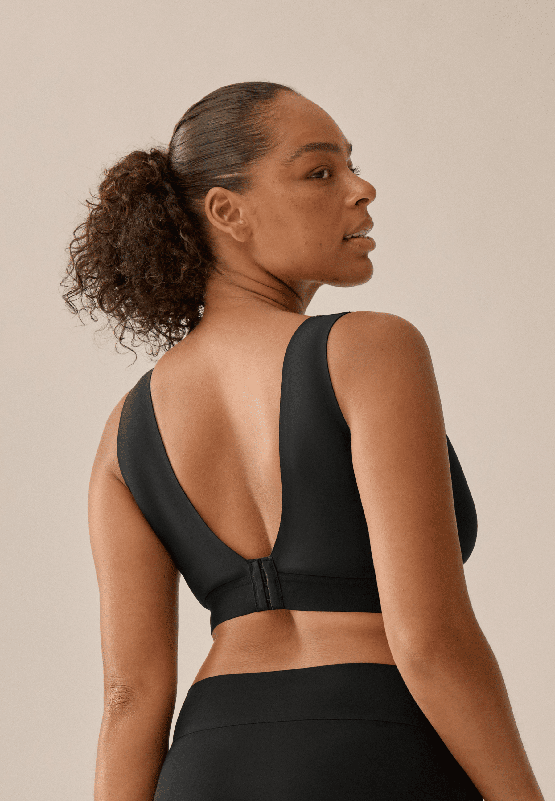 Achterzijde van vrouw die de smoothing bh in de kleur zwart van het merk Naturana draagt