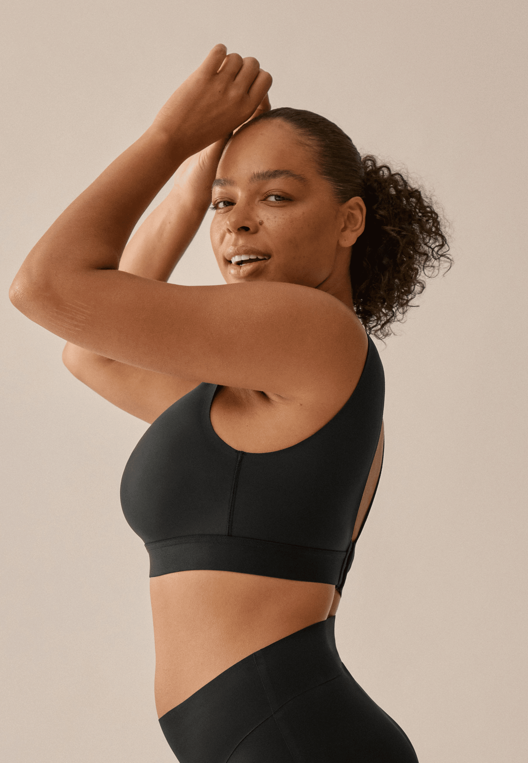 Zijde van vrouw die de smoothing bh in de kleur zwart van het merk Naturana draagt
