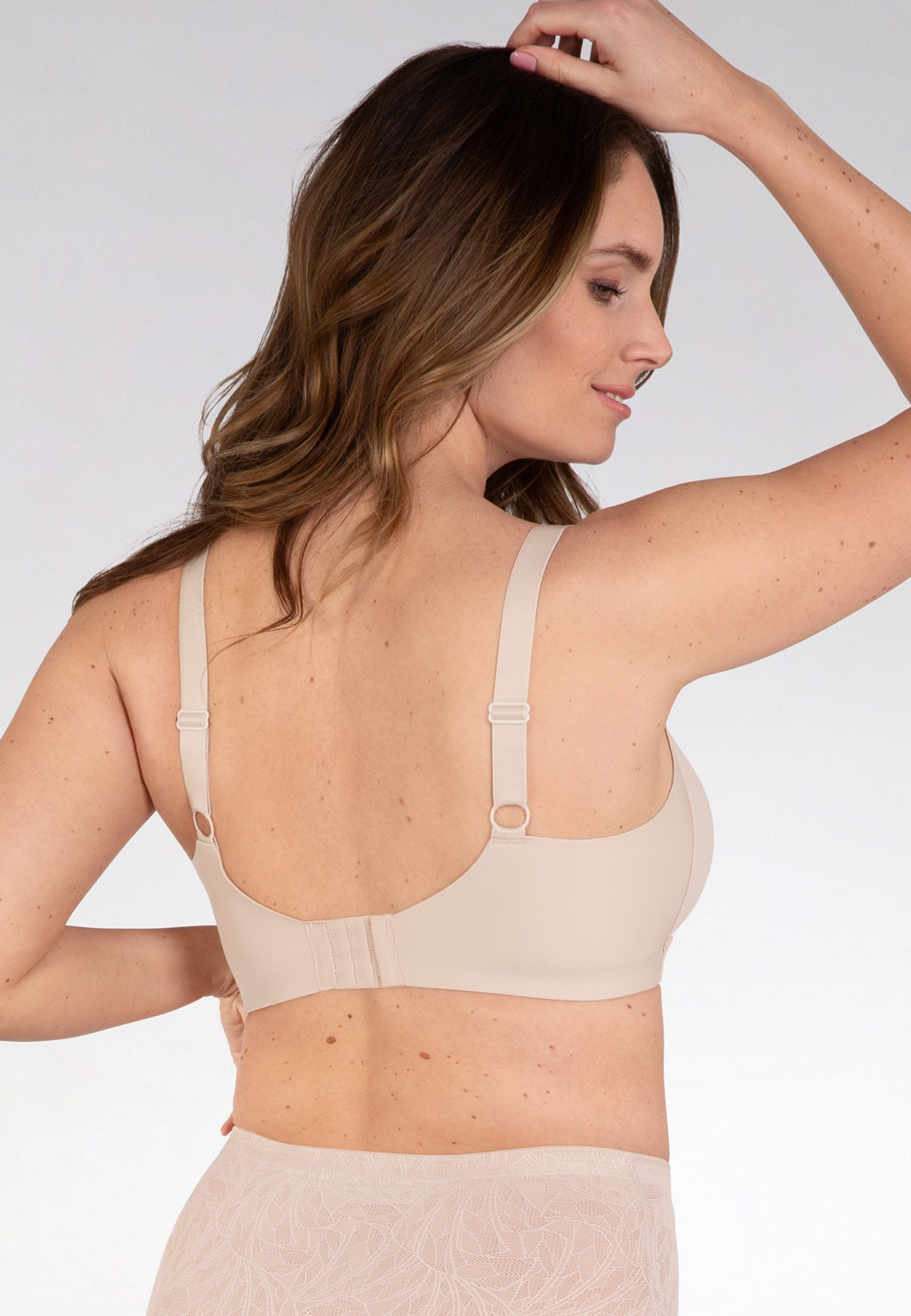Achterzijde van vrouw die de side smoother bh in de kleur beige van het merk Naturana draagt
