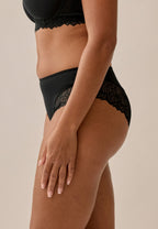 Zijde van vrouw die de hipster met gerecycled kant in de kleur zwart van het merk Naturana draagt