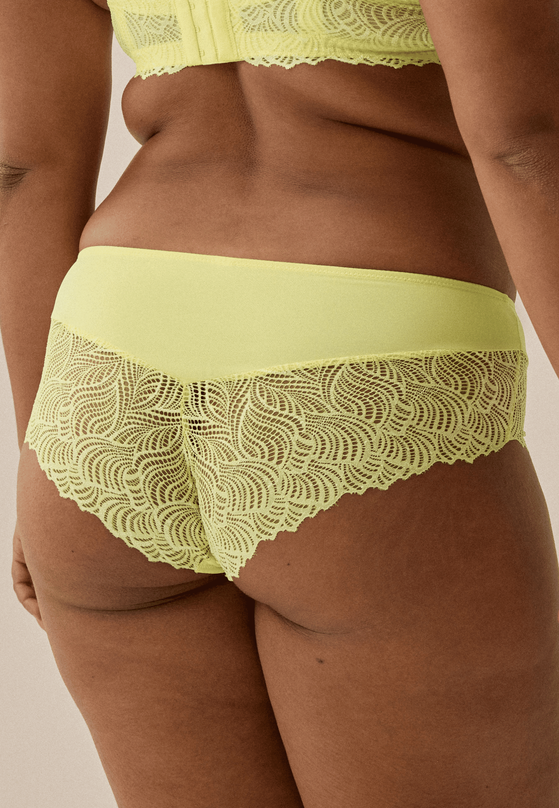 Achterzijde van vrouw die de hipster met gerecycled kant in de kleur sunny lime van het merk Naturana draagt