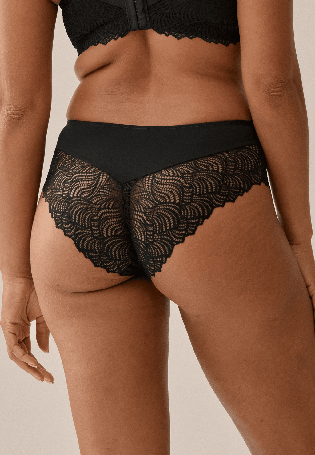 Achterzijde van vrouw die de hipster met gerecycled kant in de kleur zwart van het merk Naturana draagt