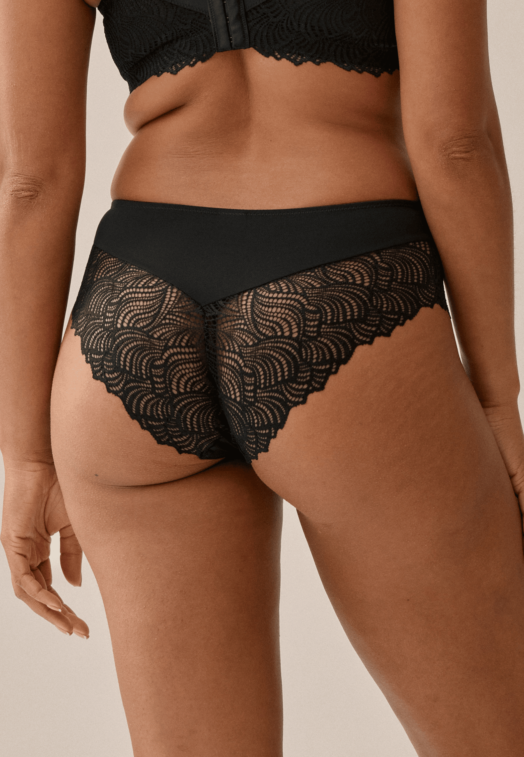 Achterzijde van vrouw die de hipster met gerecycled kant in de kleur zwart van het merk Naturana draagt