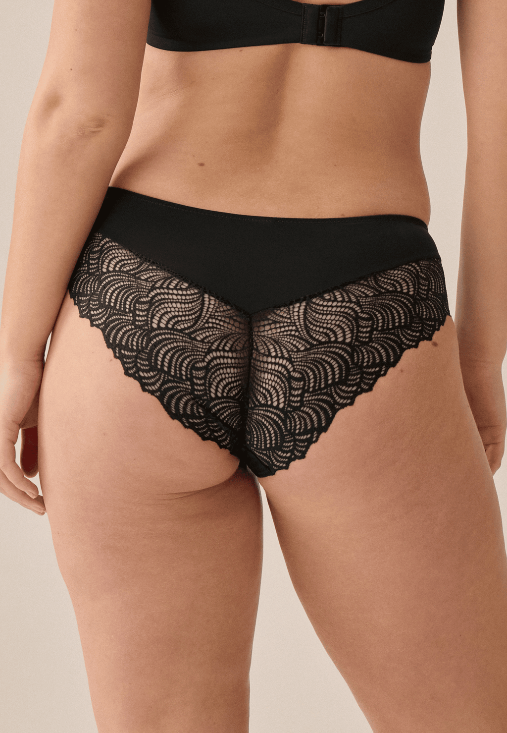 Achterzijde van vrouw die de hipster met gerecycled kant in de kleur zwart van het merk Naturana draagt