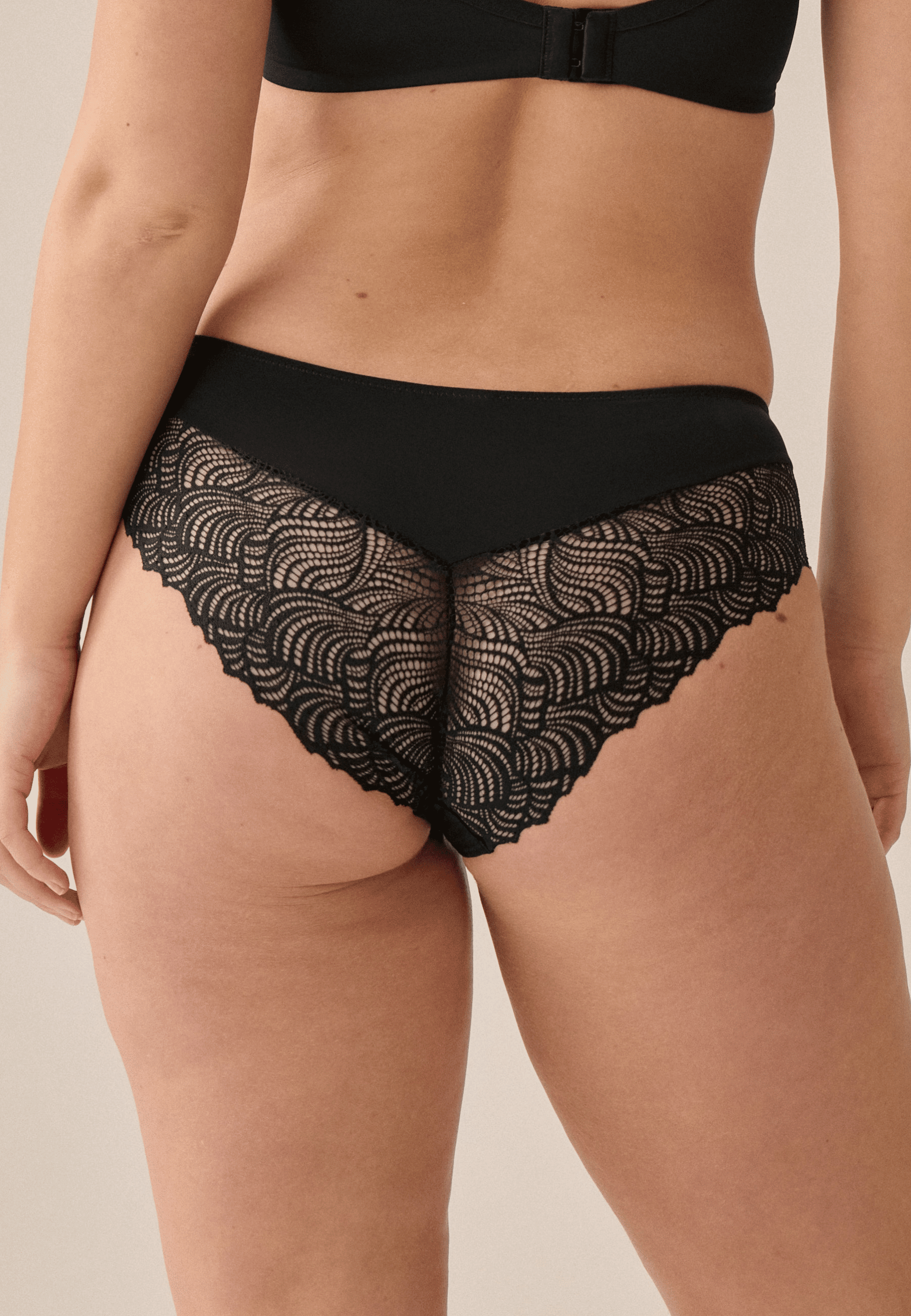 Achterzijde van vrouw die de hipster met gerecycled kant in de kleur zwart van het merk Naturana draagt