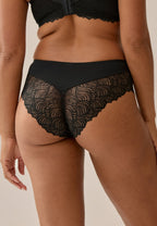 Achterzijde van vrouw die de hipster met gerecycled kant in de kleur zwart van het merk Naturana draagt