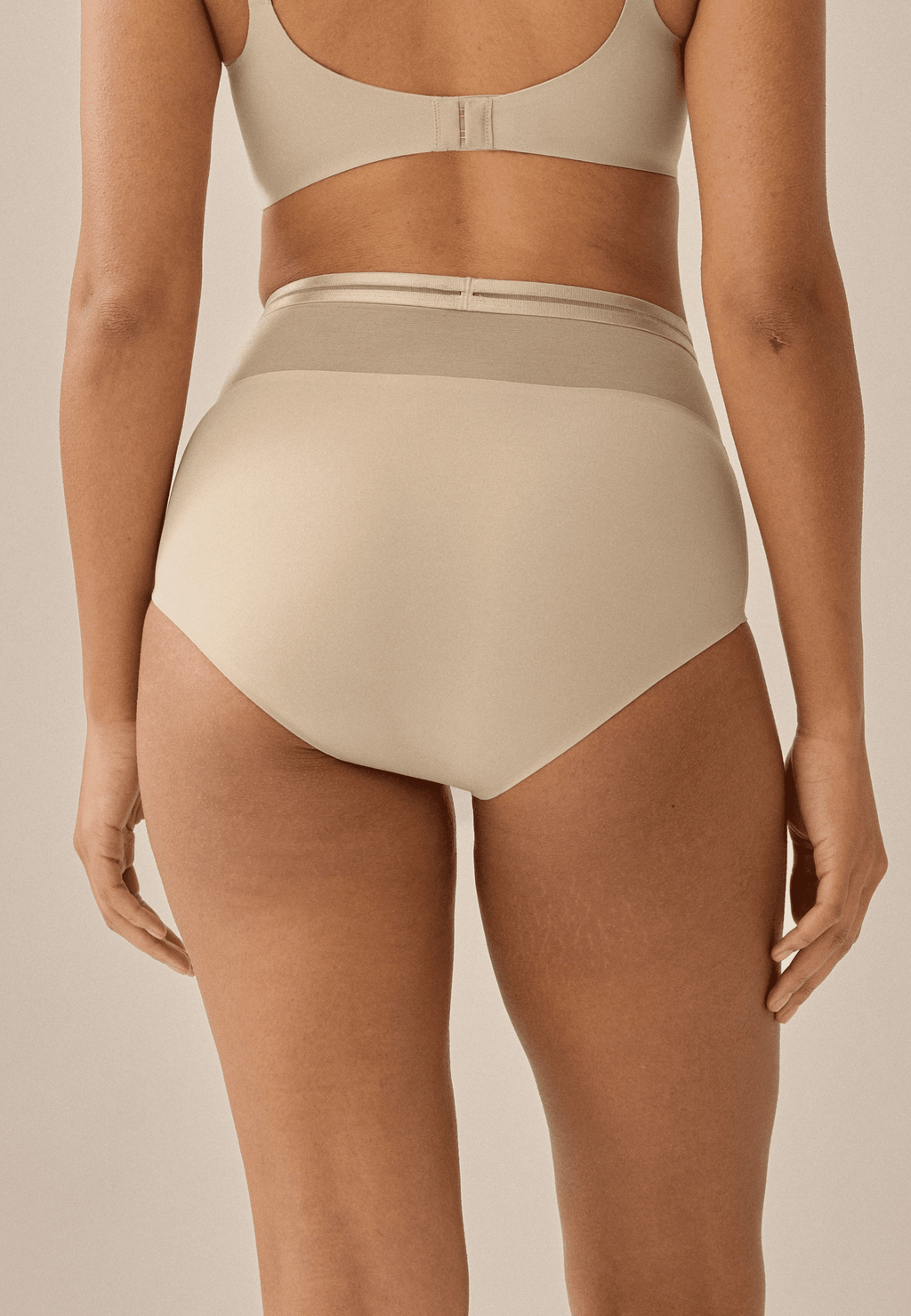 Achterzijde van vrouw die de hoge slip met mesh in de kleur beige van het merk Naturana draagt