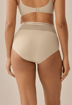Achterzijde van vrouw die de hoge slip met mesh in de kleur beige van het merk Naturana draagt