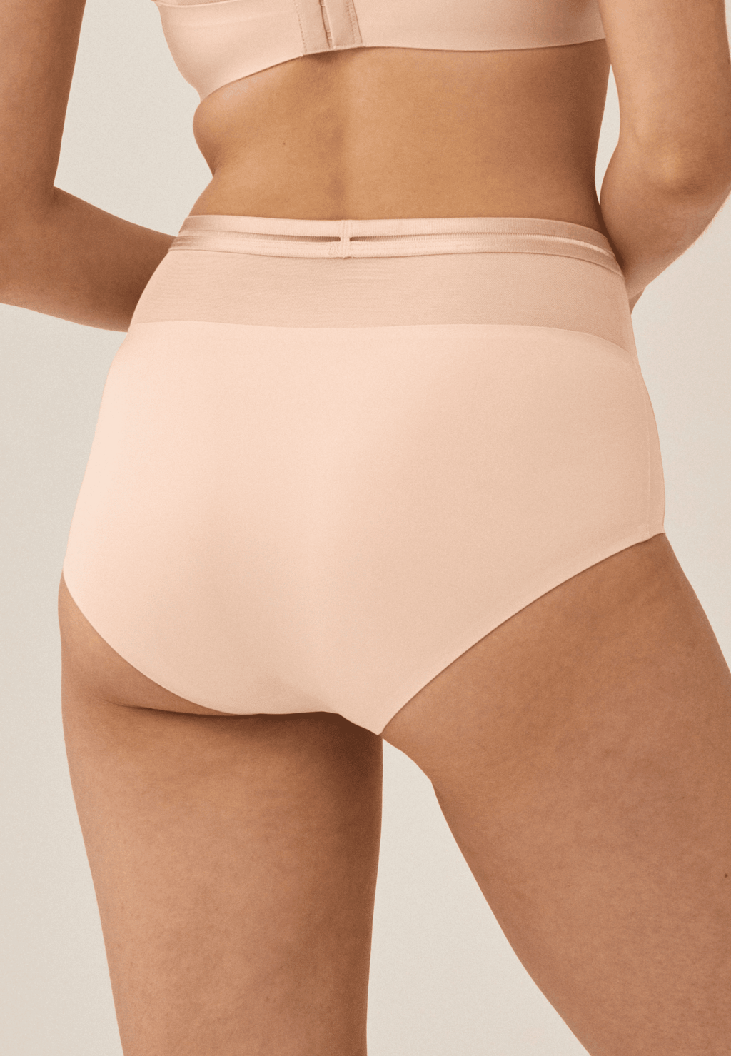 Achterzijde van vrouw die de hoge slip met mesh in de kleur beige van het merk Naturana draagt
