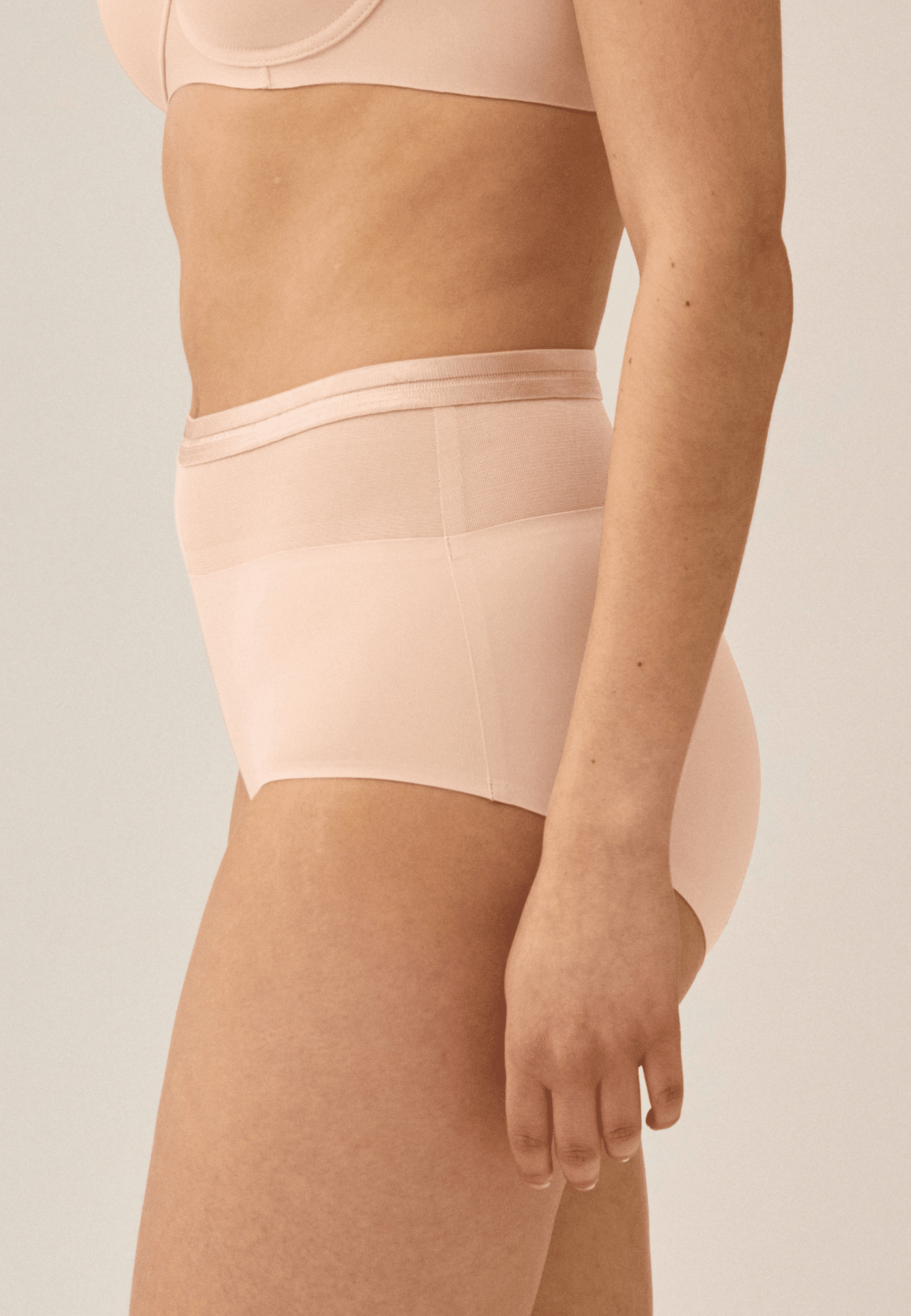 Zijde van vrouw die de hoge slip met mesh in de kleur beige van het merk Naturana draagt