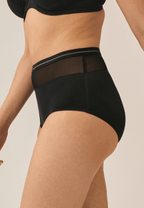 Zijde van vrouw die de hoge slip met mesh in de kleur zwart van het merk Naturana draagt