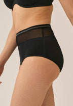 Zijde van vrouw die de hoge slip met mesh detail in de kleur zwart van het merk Naturana draagt