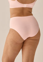 Achterzijde van vrouw die de minimizer slip met glanzend effect in de kleur blush van het merk Naturana draagt