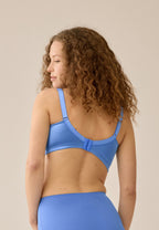 Achterzijde van vrouw die de minimizer bh met mesh detail in de kleur marina blue van het merk Naturana draagt