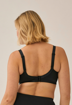 Achterzijde van vrouw die de minimizer bh met mesh detail in de kleur zwart van het merk Naturana draagt