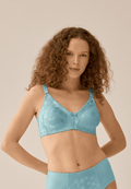 Voorzijde van vrouw die de minimizer bh met bloemenpatroon in de kleur aquamarine van het merk Naturana draagt