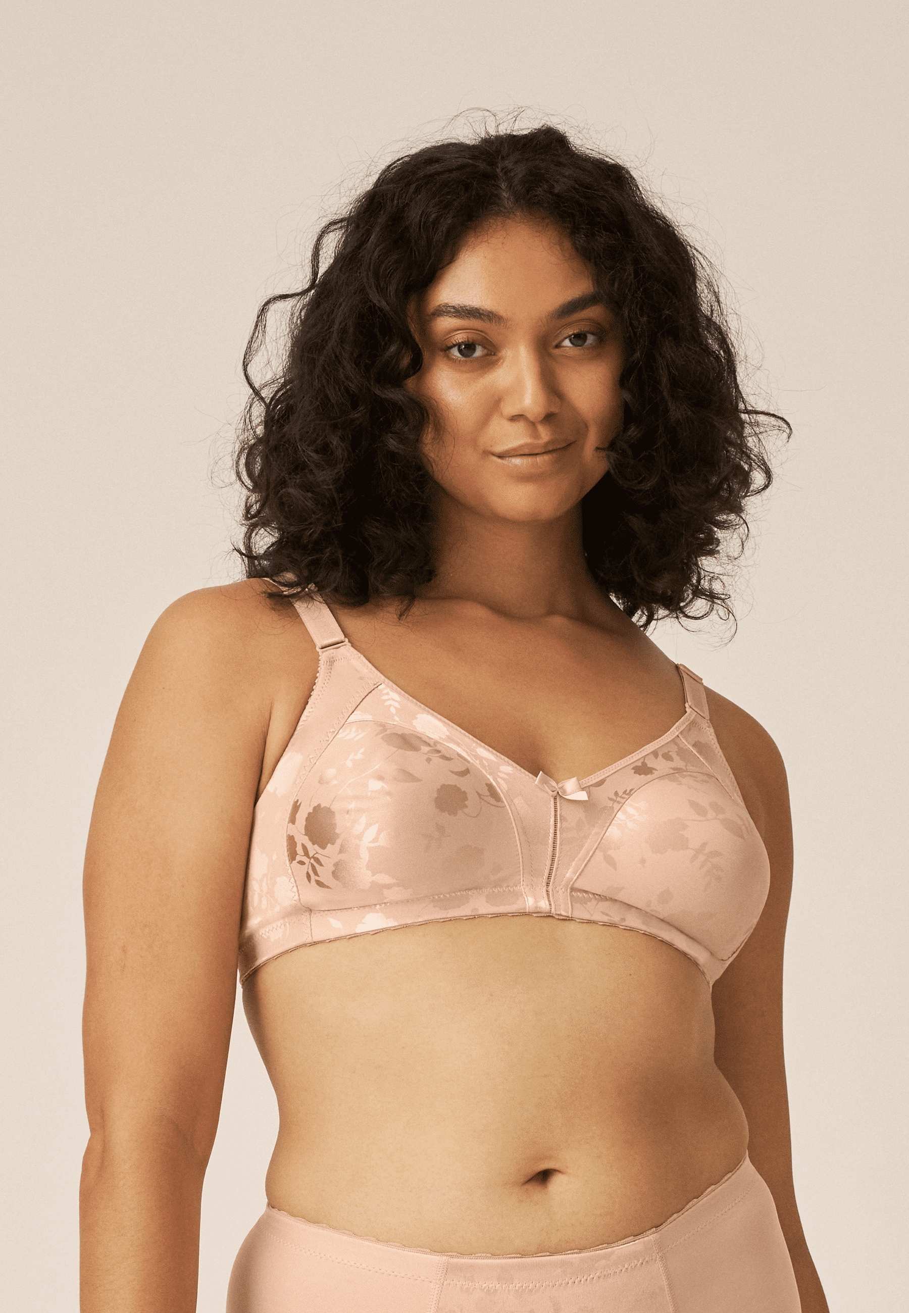 Voorzijde van vrouw die de minimizer bh met bloemenpatroon in de kleur beige van het merk Naturana draagt
