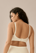 Achterzijde van vrouw die de minimizer bh met bloemenpatroon in de kleur ivoor van het merk Naturana draagt