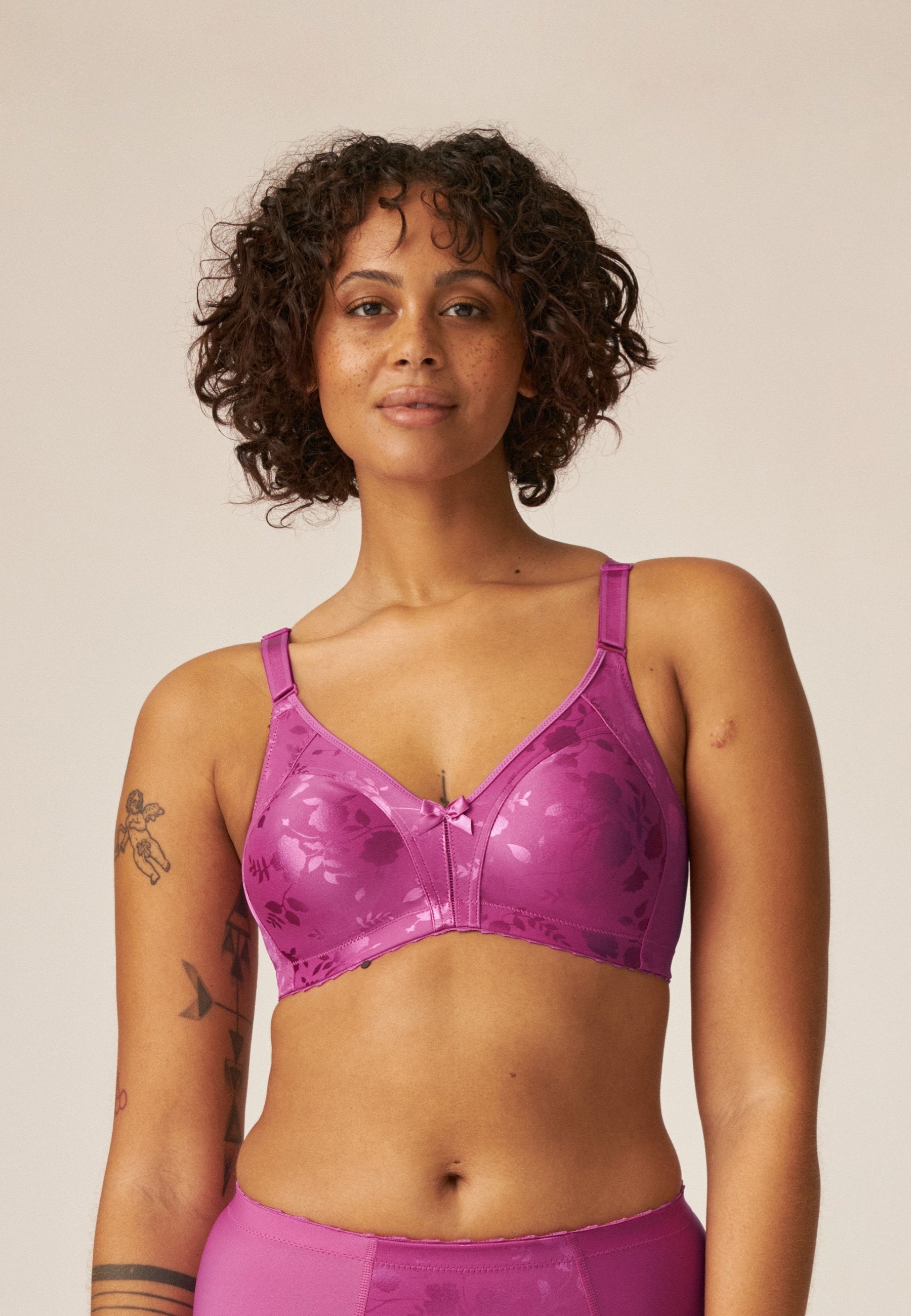 Voorzijde van vrouw die de minimizer bh met bloemenpatroon in de kleur purple orchid van het merk Naturana draagt