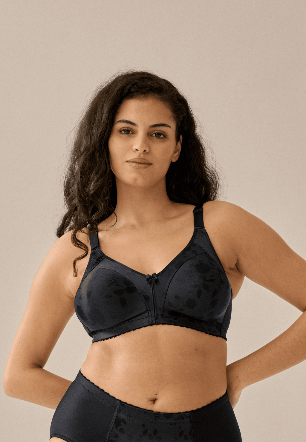Voorzijde van vrouw die de minimizer bh met bloemenpatroon in de kleur zwart van het merk Naturana draagt