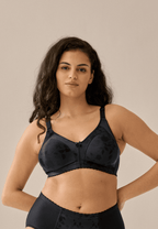 Voorzijde van vrouw die de minimizer bh met bloemenpatroon in de kleur zwart van het merk Naturana draagt
