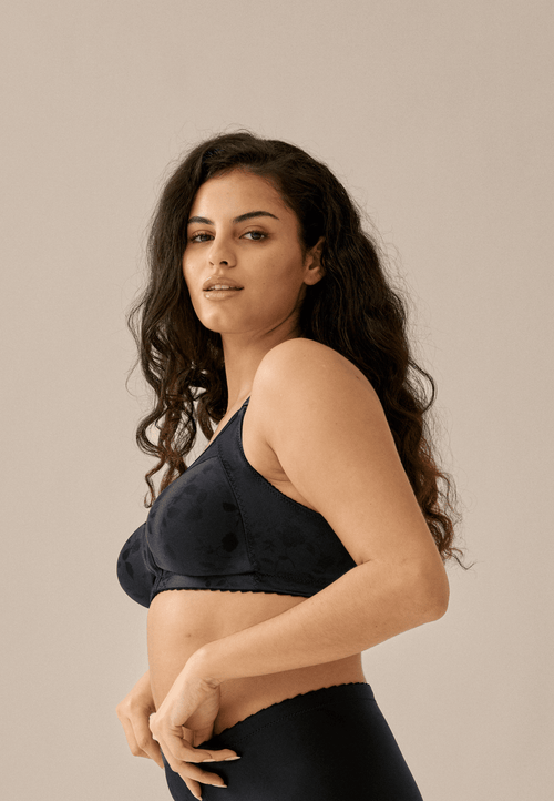 Zijde van vrouw die de minimizer bh met bloemenpatroon in de kleur zwart van het merk Naturana draagt