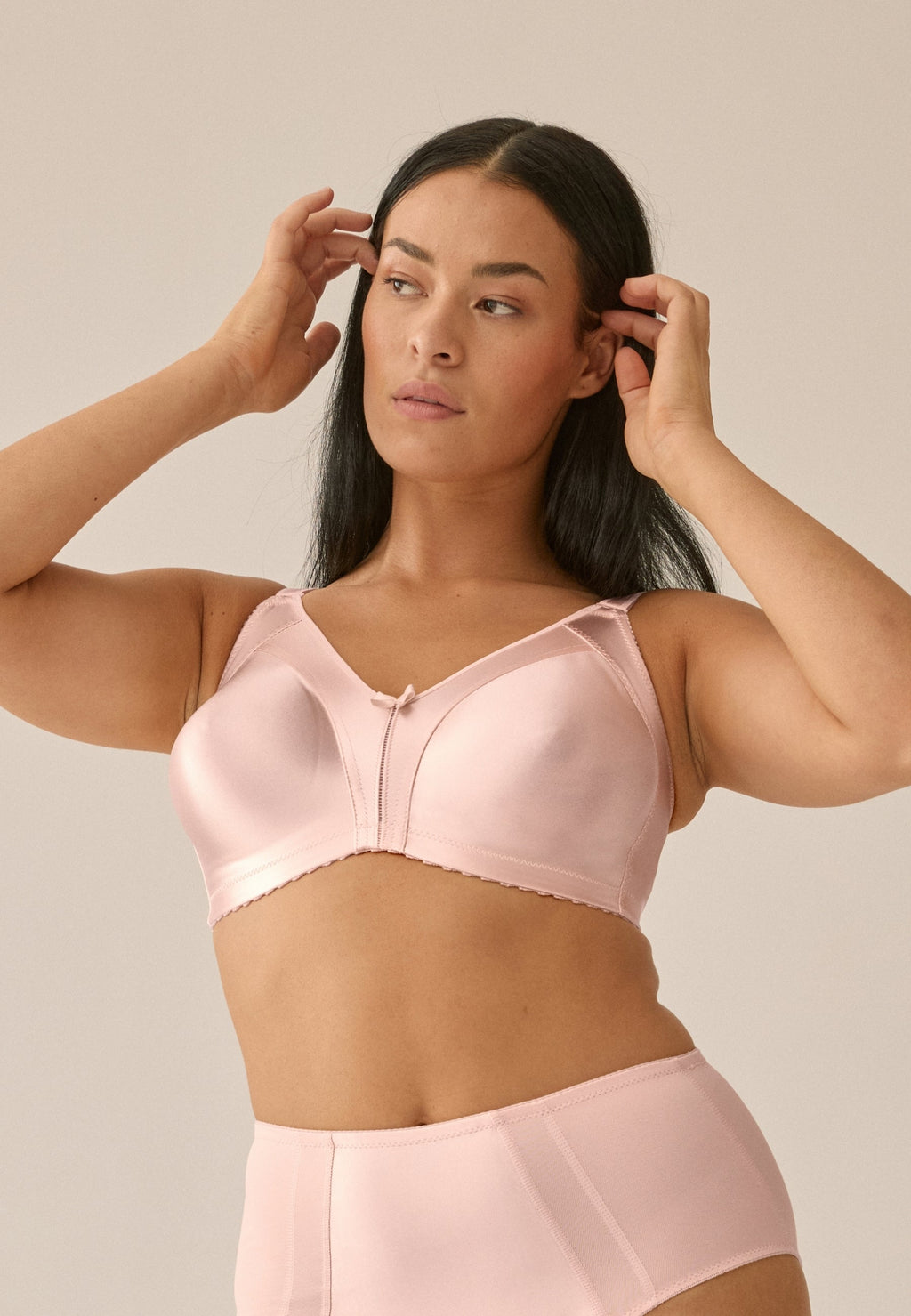 Voorzijde van vrouw die de minimizer bh met glanzend effect in de kleur blush van het merk Naturana draagt