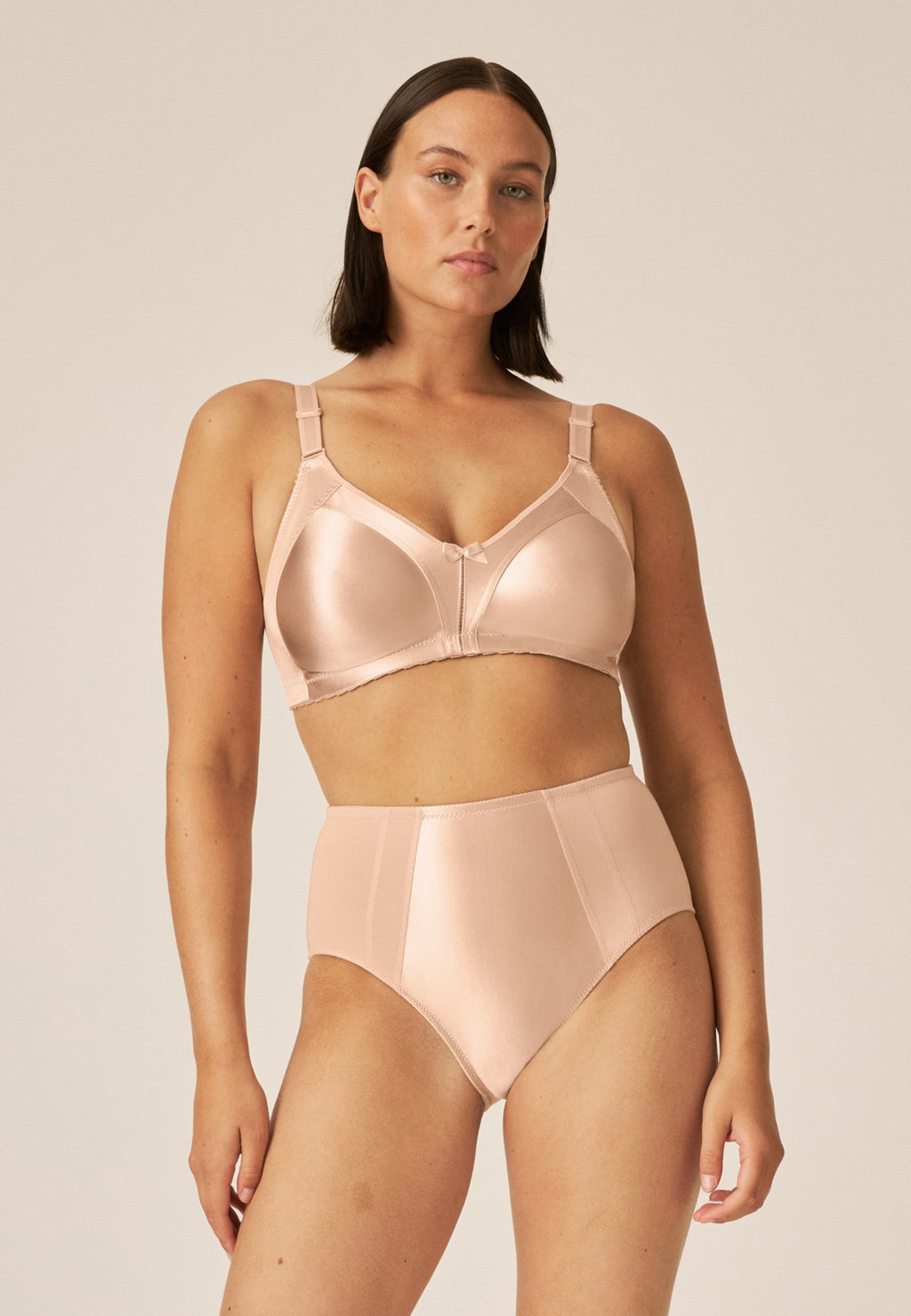 Voorzijde van vrouw die de minimizer bh en minimizer slip met glanzend effect in de kleur beige van het merk Naturana draagt