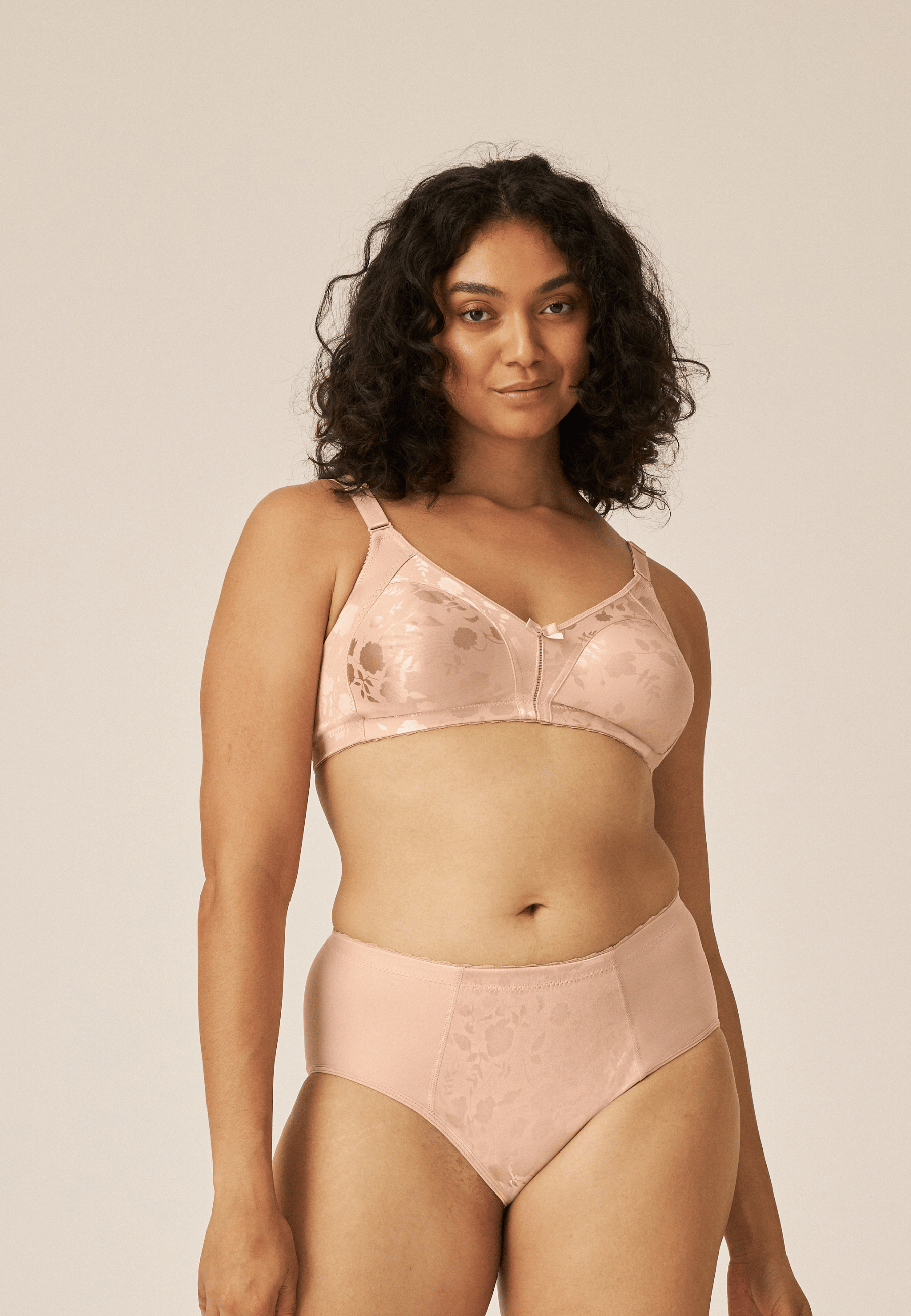 Voorzijde van vrouw die de minimizer bh met bloemenpatroon en de minimizer slip met bloemenpatroon in de kleur beige van het merk Naturana draagt