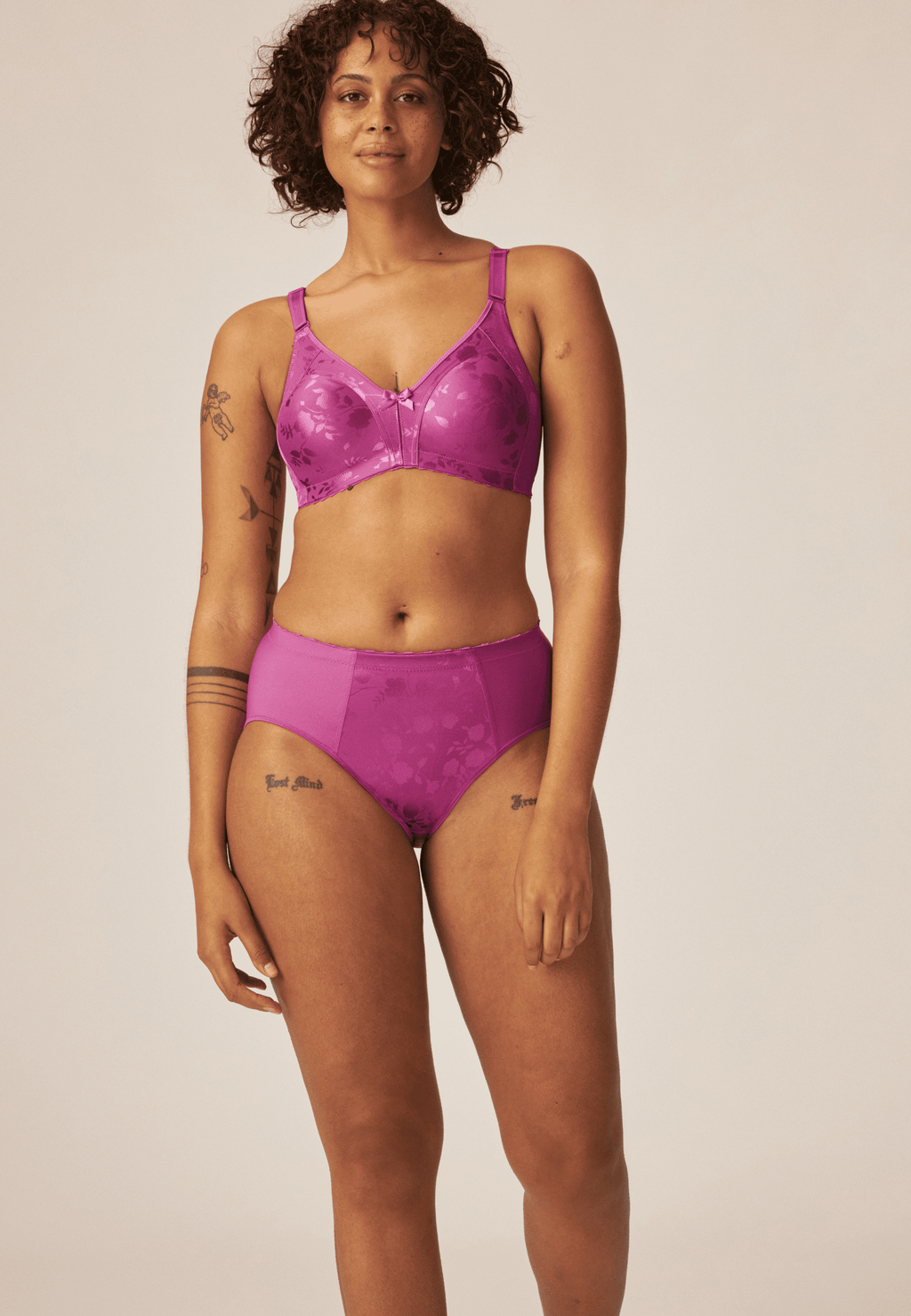 Voorzijde van vrouw die de minimizer bh met bloemenpatroon en de minimizer slip met bloemenpatroon in de kleur purple orchidvan het merk Naturana draagt