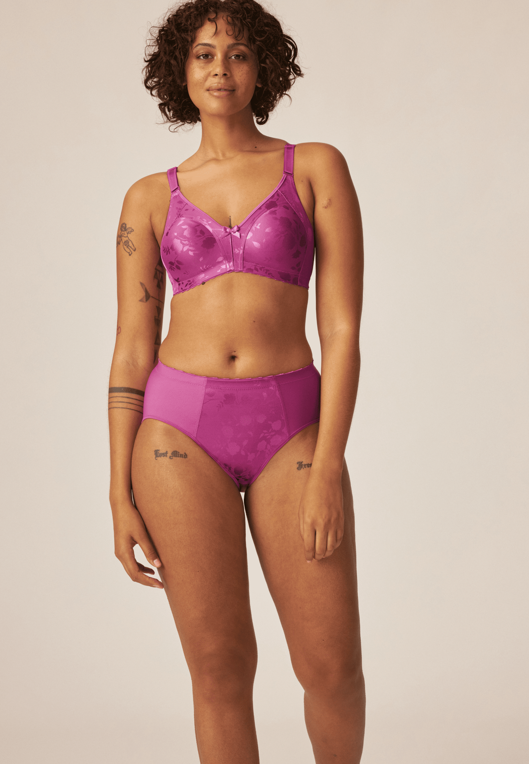 Voorzijde van vrouw die de minimizer bh met bloemenpatroon en de minimizer slip met bloemenpatroon in de kleur purple orchidvan het merk Naturana draagt