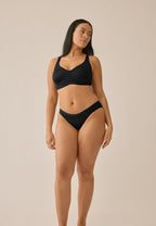 Voorzijde van vrouw die de minimizer bh en slip in de kleur zwart van het merk Naturana draagt