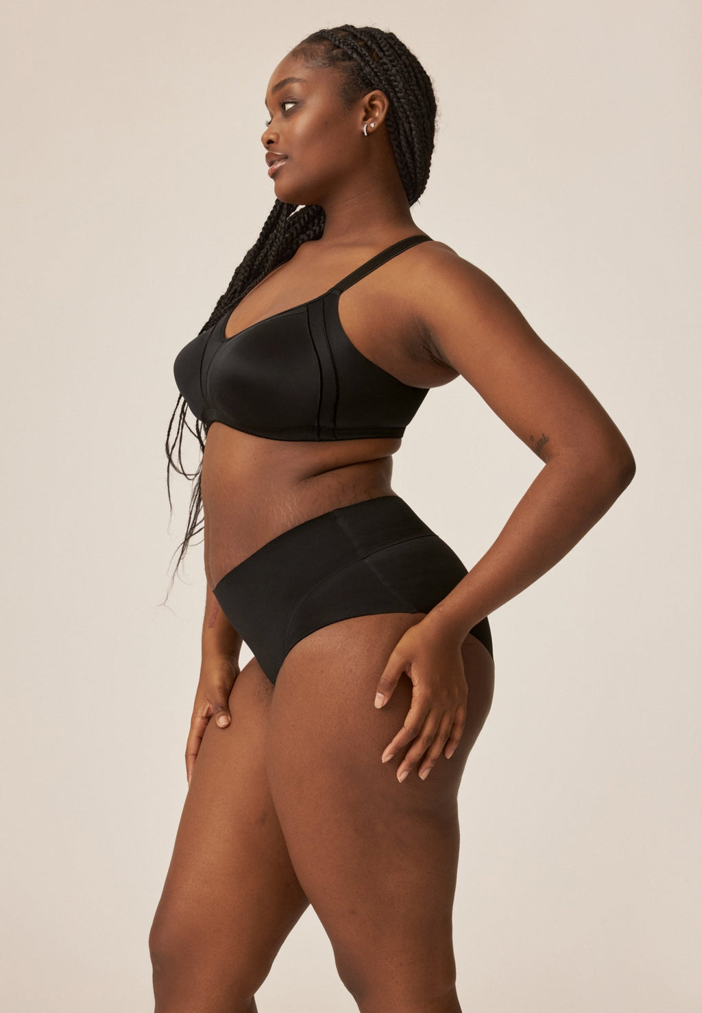 Zijde van vrouw die de minimizer bh met side smoother in de kleur zwart van het merk Naturana draagt