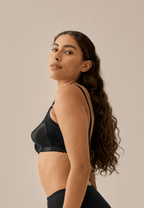 Zijde van vrouw die de minimizer bh in de kleur zwart van het merk Naturana draagt