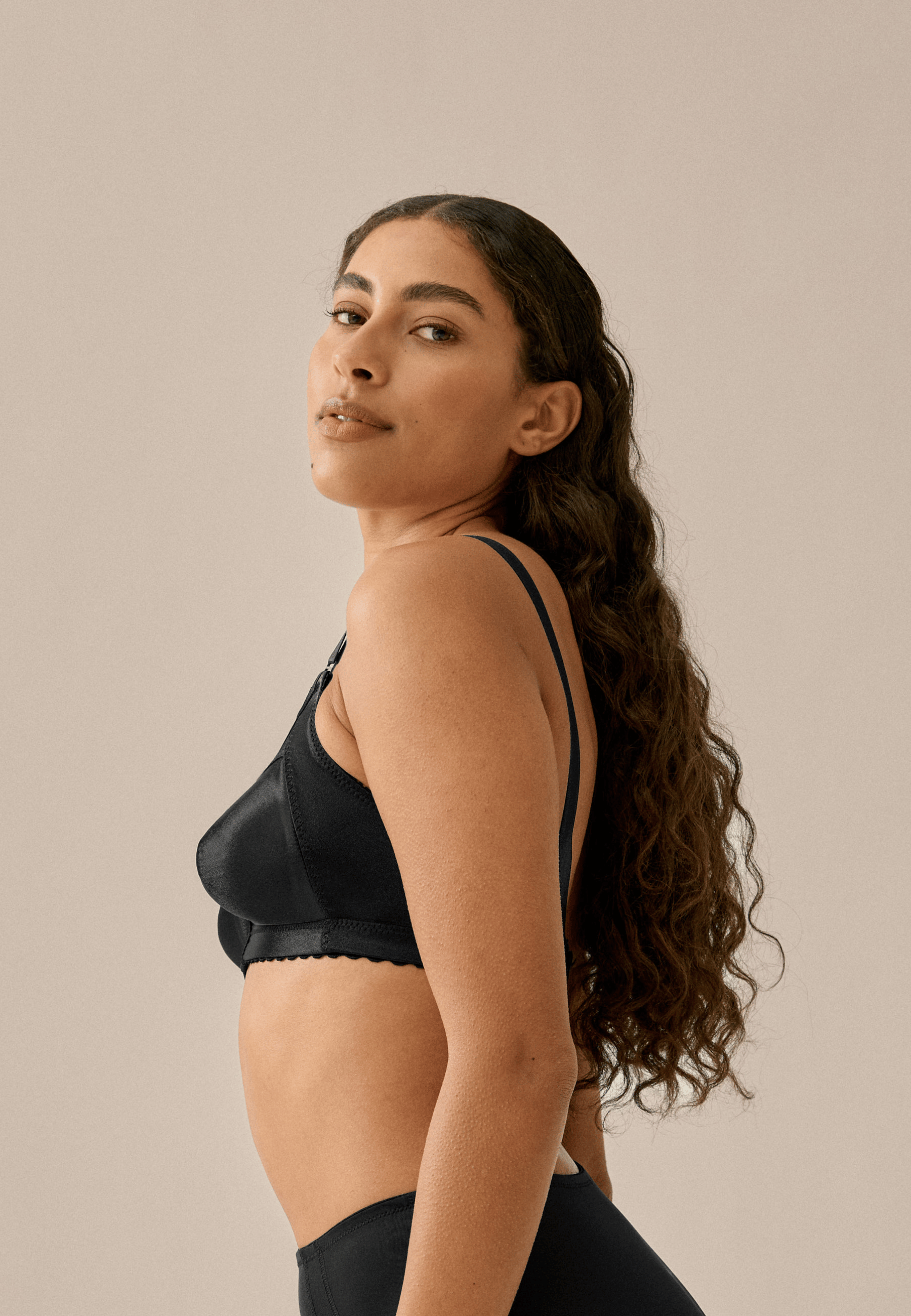 Zijde van vrouw die de minimizer bh in de kleur zwart van het merk Naturana draagt