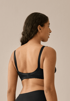 Achterzijde van vrouw die de minimizer bh in de kleur zwart van het merk Naturana draagt
