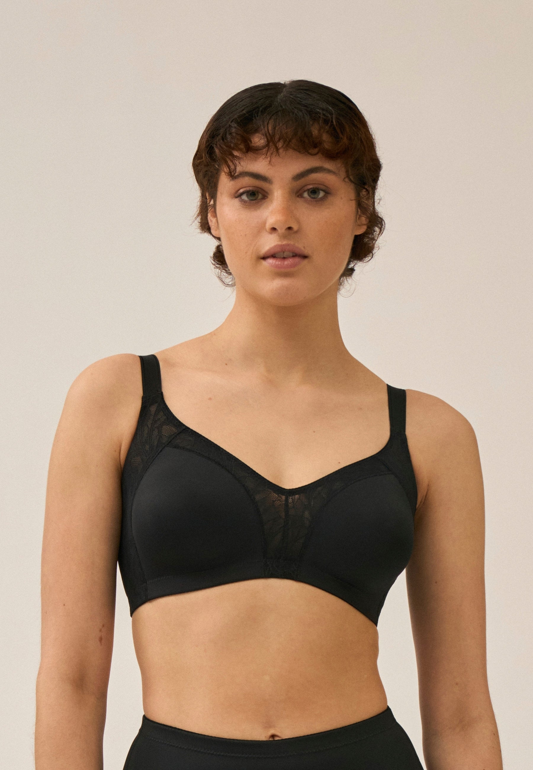 Voorzijde van vrouw die de minimizer bh met kant in de kleur zwart van het merk Naturana draagt