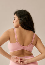 Achterzijde van vrouw die de  minimizer bh met side smoother in de kleur pink rose van het merk Naturana draagt