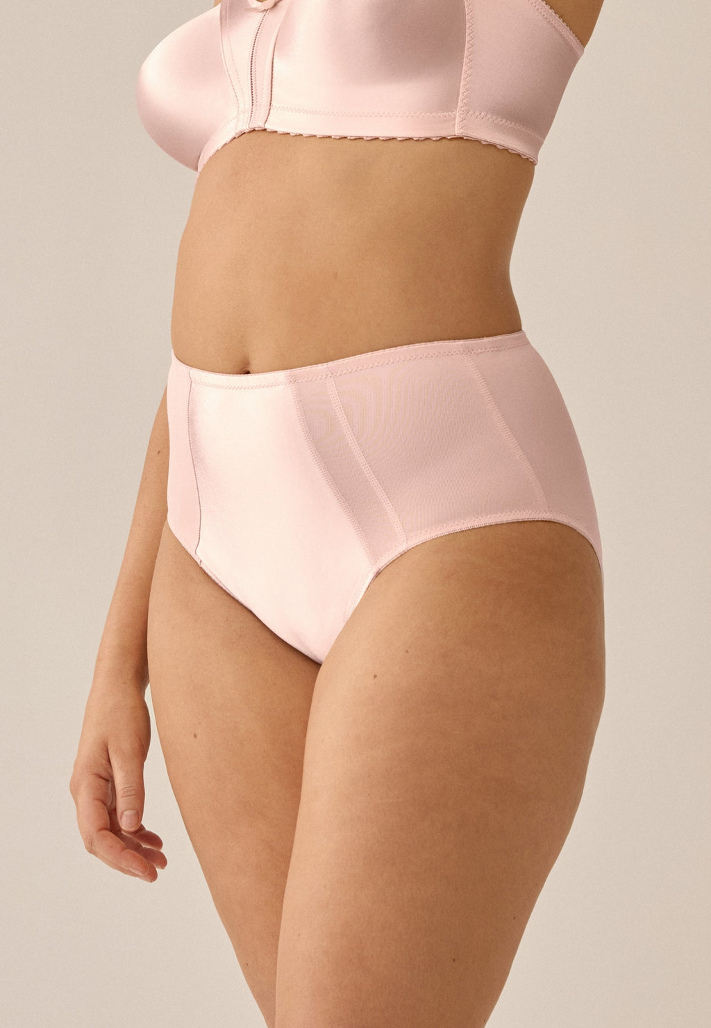 Zijde van vrouw die de minimizer slip met glanzend effect in de kleur blush van het merk Naturana draagt