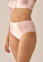 Zijde van vrouw die de minimizer slip met glanzend effect in de kleur blush van het merk Naturana draagt