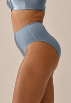 Zijde van vrouw die de minimizer slip met glanzend effect in de kleur moonlight blue van het merk Naturana draagt