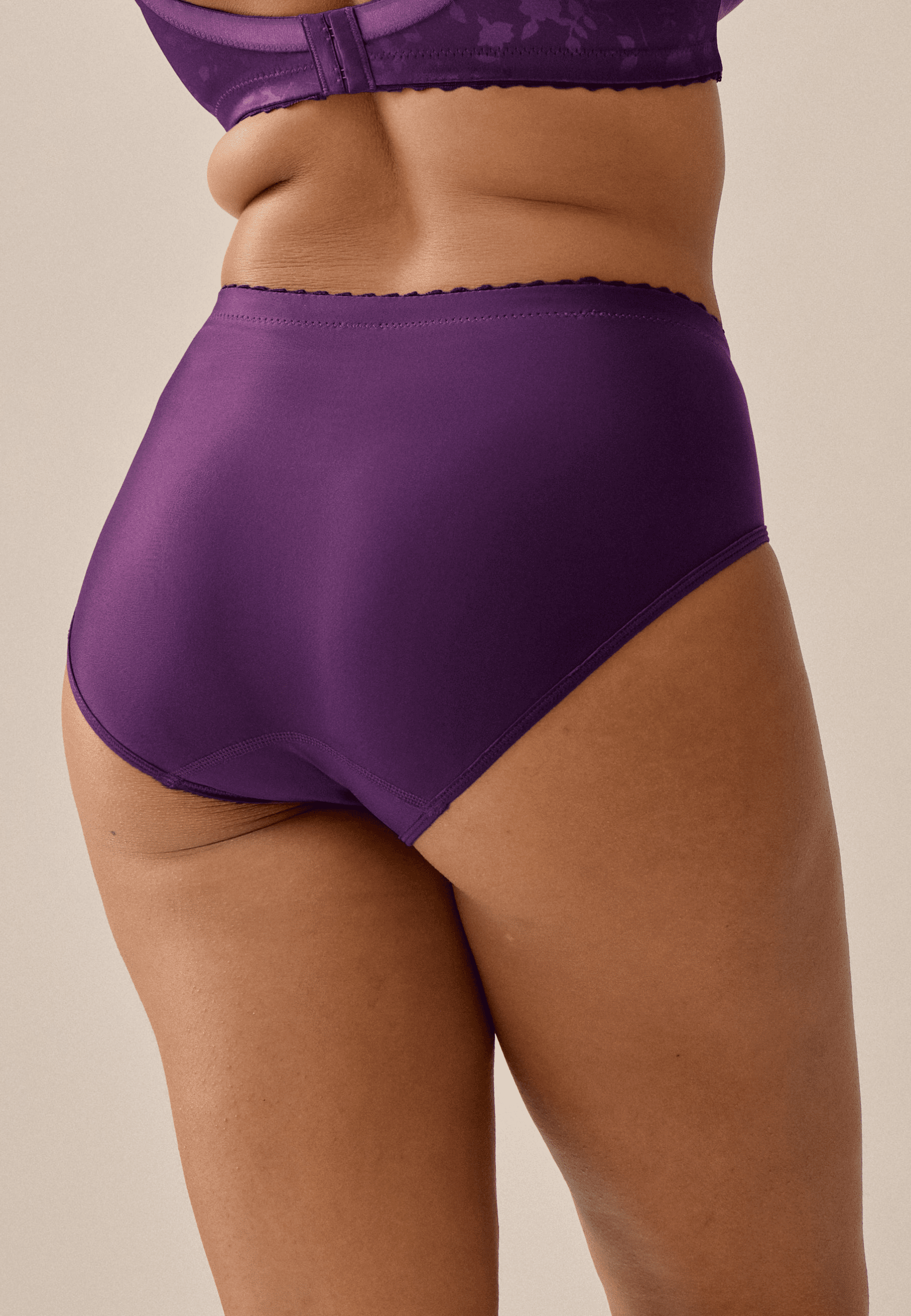 Achterzijde van vrouw die de minimizer slip met bloemenpatroon in de kleur beetroot van het merk Naturana draagt