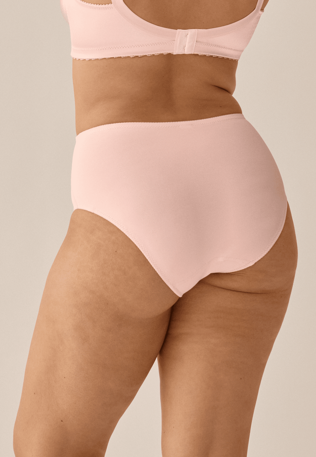 Achterzijde van vrouw die de minimizer slip in de kleur blush van het merk Naturana draagt