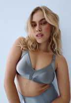 Voorzijde van vrouw die de minimizer bh met glanzend effect en minimizer slip in de kleur moonlight blue van het merk Naturana draagt